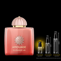 Amouage Guidance 46 perfume bottle in a coral pink shade with a gold cap, shown next to three small spray vials indicating different spray counts (2ml, 5ml, 10ml) on a black background.