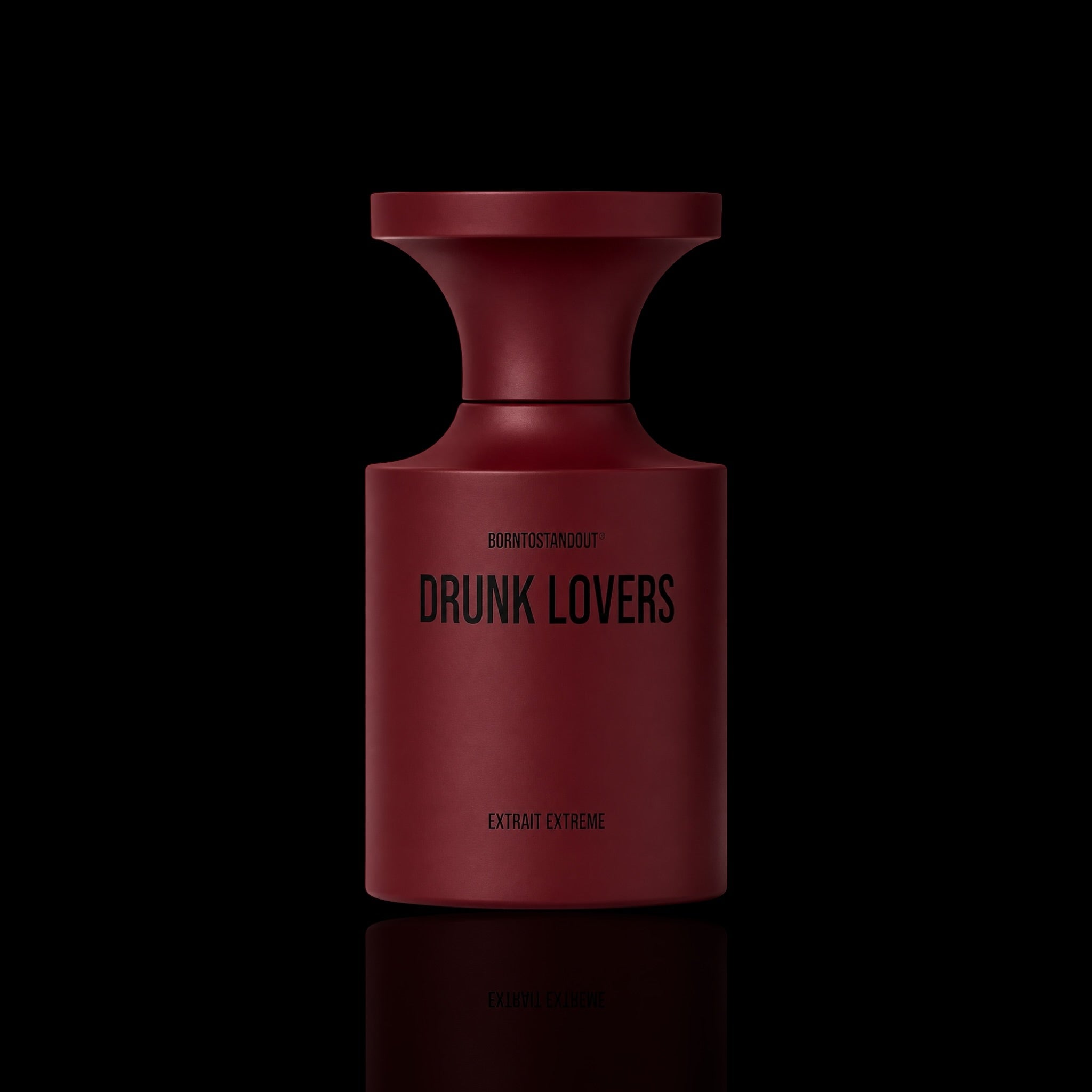A matte dark red cylindrical bottle with a flared top, labeled 'DRUNK LOVERS' and 'EXTRACT EXTREME', centered on a black background with a faint reflection below.